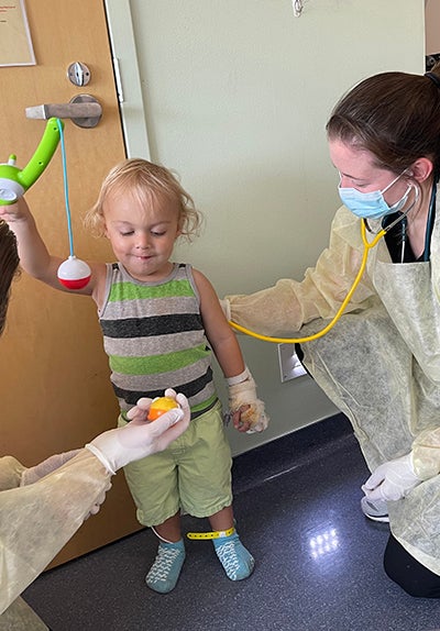 Pediatrics resident exams a boy playing with a toy.