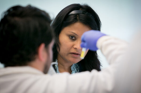 Dr. Asuthkar looks at a test tube, being held up by a colleague
