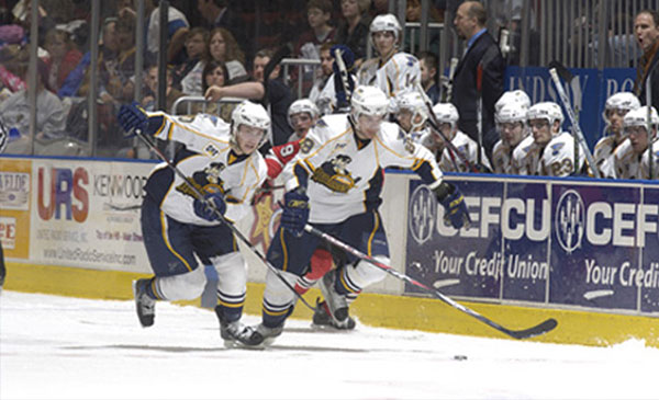 2 Hockey Players Racing for a Puck at a Rivermen Hockey Game