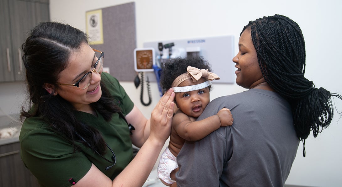 University Pediatrics Nurse measures the head of a baby