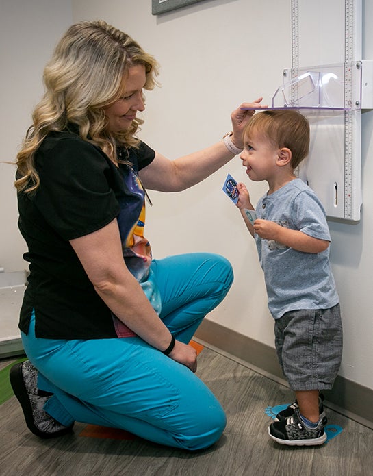 University Pediatrics nurse measures height of boy