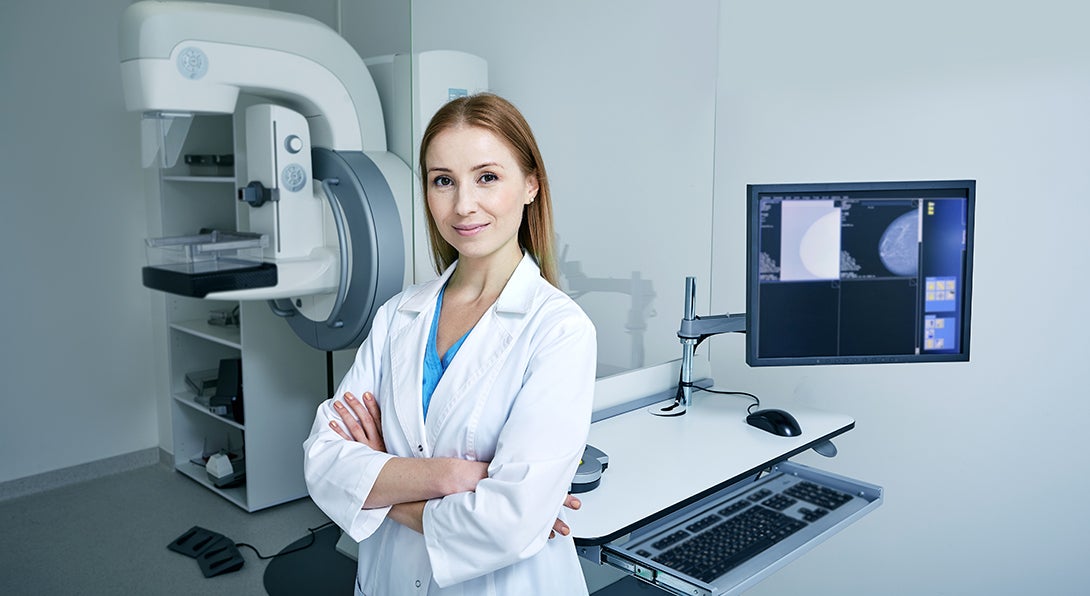 Breast imaging fellow stands in front of a mammogram machine