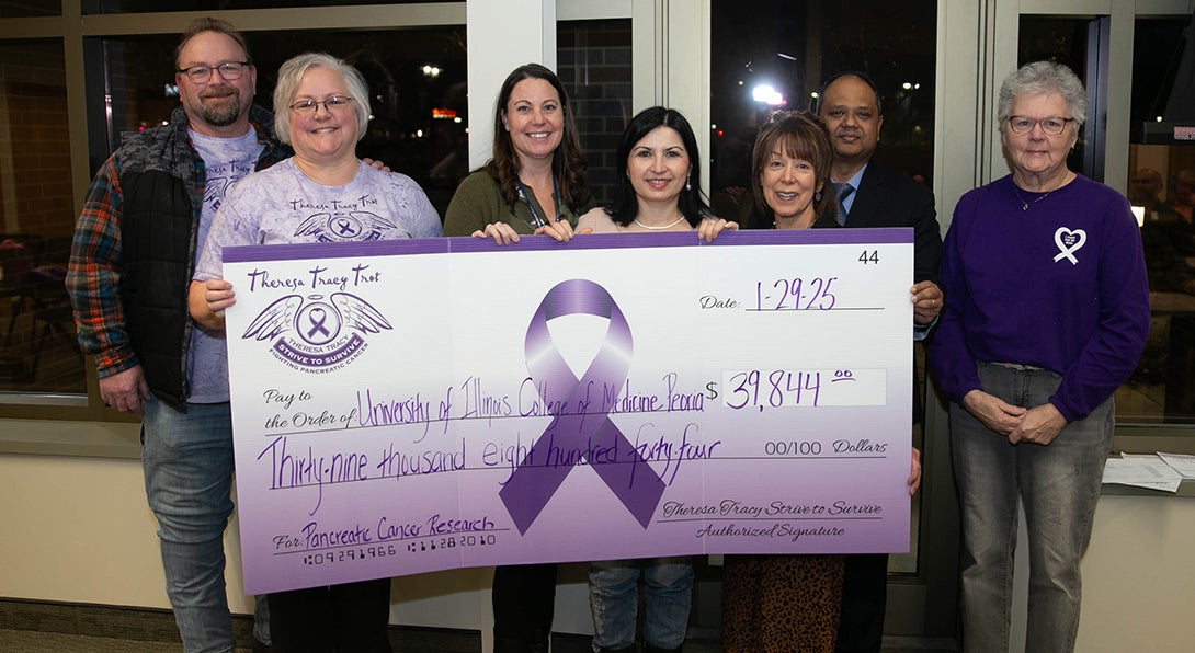 The Theresa Tracy Trot organization presents a check for $39,844 to the University of Illinois College of Medicine Peoria to support pancreatic cancer research