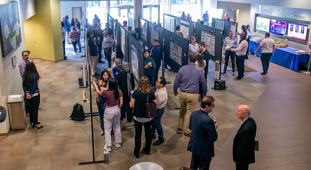 Research Day presenters speak with faculty about their research posters